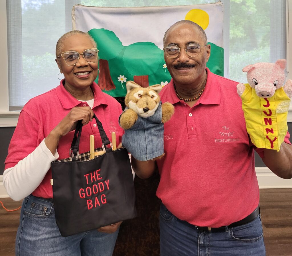 Two puppeteers stand with a wolf puppet and a pig puppet